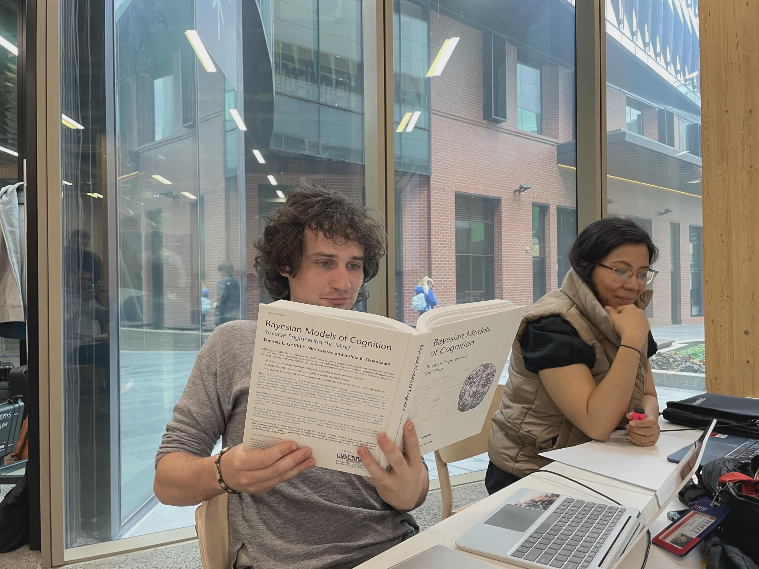 Fletcher Scott at the ADM+S Hackathon holding a book